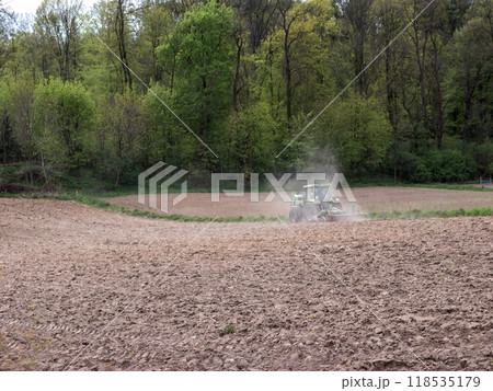 Farm tractor harrowing arable field 118535179