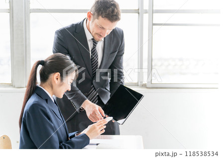 学校・塾でスマホのアプリを使って英語を勉強する中学生・高校生と欧米人の先生・塾講師 学校・塾でスマホのアプリを使って英語を勉強する中学生・高校生と欧米人の先生・塾講師 118538534