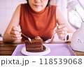 Women hands holding a spoon and eating tasty chocolate cake on table 118539068