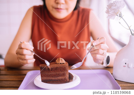 Women hands holding a spoon and eating tasty chocolate cake on table 118539068