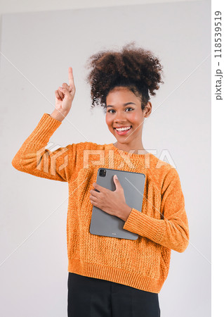 Smiling african american woman hand holding tablet and pointing upward. Isolated on white background. 118539519