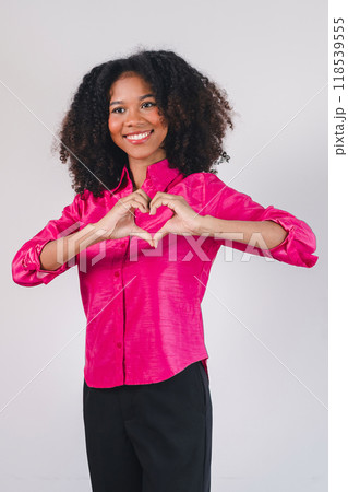 Smiling African American woman making a heart gesture with her hands, expressing love and positivity. Smiling African American woman making a heart gesture with her hands, expressing love and positivity. 118539555