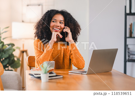 Smiling African American Woman on Phone Call at Desk While Working at Home. Smiling African American Woman on Phone Call at Desk While Working at Home. 118539651
