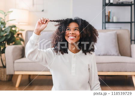 Smiling African American Woman Fluffing Her Curly Hair Indoors. Smiling African American Woman Fluffing Her Curly Hair Indoors. 118539729