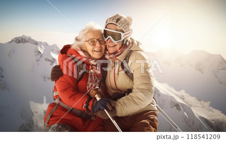 Couple of elderly women clad in ski gear share a heartwarming embrace at the snowy summit of a mountain 118541209