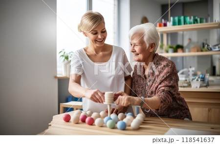 A medical professional engages in therapeutic exercises with an elderly woman in a wheelchair, utilizing a ball and various aids, exemplifying compassionate care and rehabilitation support in the 118541637