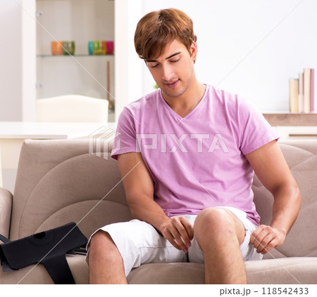 Injured man recovering at home from sports injury Injured man recovering at home from sports injury 118542433