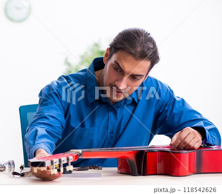 Young male repairman repairing guitar Young male repairman repairing guitar 118542626