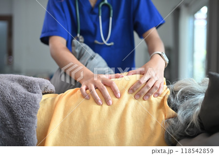 Physiotherapist massaging back muscles in area of shoulder blade of mature female patient 118542859