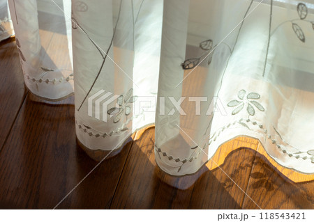 風に揺れるレース生地のカーテンの裾 118543421