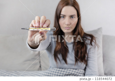 Woman caught a cold, got sick, she shows mercury thermometer with a temperature of 37,6 C. 118544072