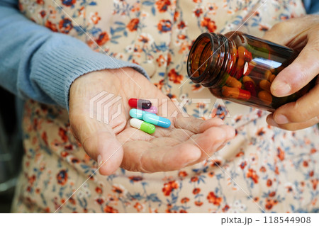 Asian elderly woman holding pill drug in hand, strong healthy medical concept. 118544908