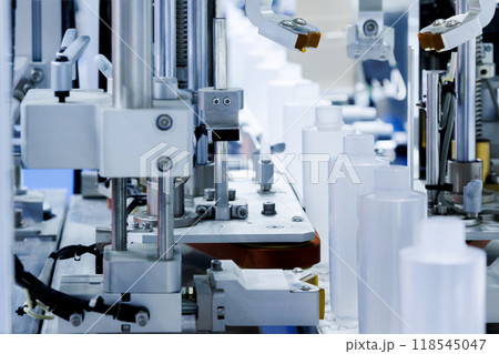 robot arm moving plastic bottle to conveyor belt of auto capping and labeling machine at cosmetic and skin care manufacturing. cosmetic industry and ai technology machinery concept. 118545047