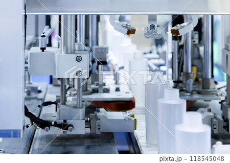 robot arm moving plastic bottle to conveyor belt of auto capping and labeling machine at cosmetic and skin care manufacturing. cosmetic industry and ai technology machinery concept. robot arm moving plastic bottle to conveyor belt of auto capping and labeling machine at cosmetic and skin care manufacturing. cosmetic industry and ai technology machinery concept. 118545048