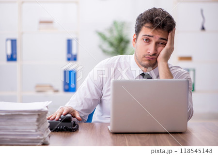 Young male employee and too much work in the office 118545148