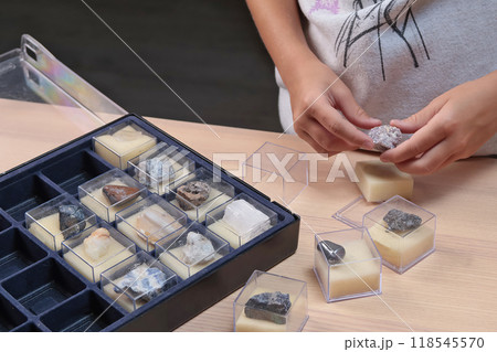 Schoolgirl explores collection of rocks and minerals and show off black onyx. School and learning. Useful resources. Young geologist.  118545570