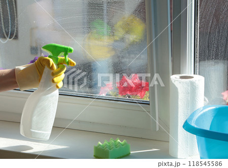 Woman wearing rubber gloves washing window in house. Cleaning and cleanliness, detergents. Woman wearing rubber gloves washing window in house. Cleaning and cleanliness, detergents. 118545586