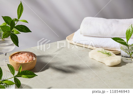 High angle shot photo on spa table with blank space in center for product presentation, green plants, white towel, spa pink salt and white soap displayed around 118546943