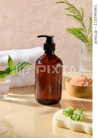 An amber pump bottle without label placed in center with many stocks of spa theme decorated around. Close up front angle shot, mock up for advertising 118546961