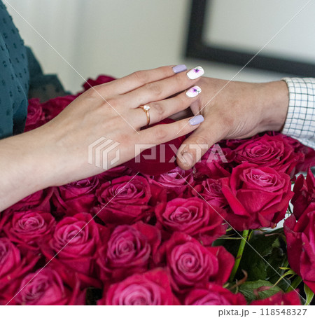 Betrothal ring on woman hand with pink bouqet of roses. Romantic event. 118548327