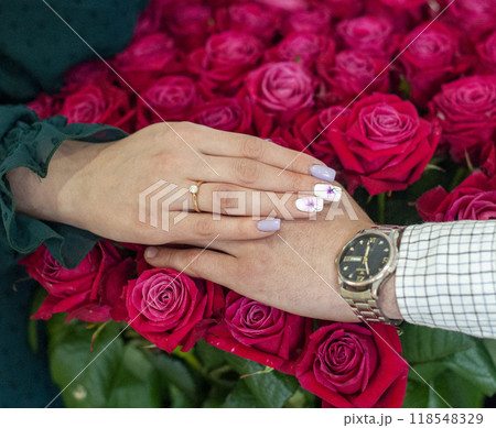 Betrothal ring on woman hand with pink bouqet of roses. Romantic event. 118548329