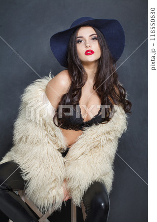 Cute fashion model woman in blue classic hat and white fur coat posing indoor Cute fashion model woman in blue classic hat and white fur coat posing indoor 118550630