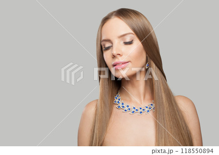 Smiling jewellery model woman wearing stylish gold earring and necklace with blue crystal sapphire Smiling jewellery model woman wearing stylish gold earring and necklace with blue crystal sapphire 118550894