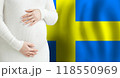 Pregnant woman belly against Swedish flag background. Demographics and pregnancy in Sweden concept 118550969