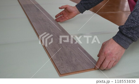 male hands laying laminate floor panels on soft insulation on the floor in an apartment or house, beige laminate flooring with wood pattern and green floor underlay in the room male hands laying laminate floor panels on soft insulation on the floor in an apartment or house, beige laminate flooring with wood pattern and green floor underlay in the room 118553830