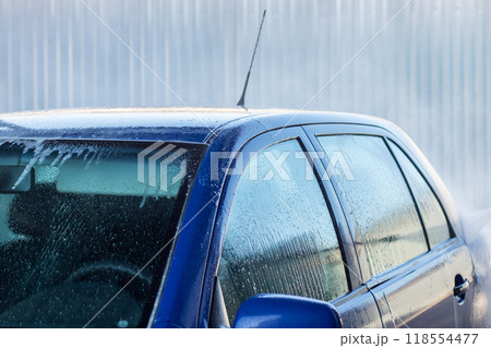 A blue car is being thoroughly washed with soap and water A blue car is being thoroughly washed with soap and water 118554477