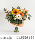 Vibrant bouquet of sunflowers, daisies, orange gerberas, and eucalyptus wrapped in paper, standing 118556159