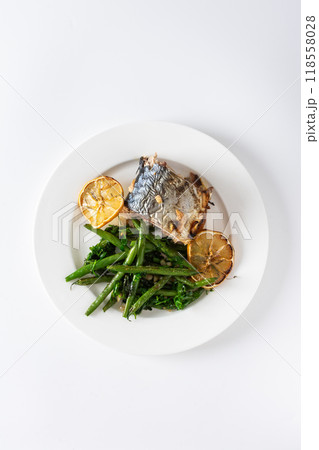 Savor the wholesome flavors of baked green beans with onions and baked mackerel, elegantly plated on a white background, ideal for a nutritious 118558028