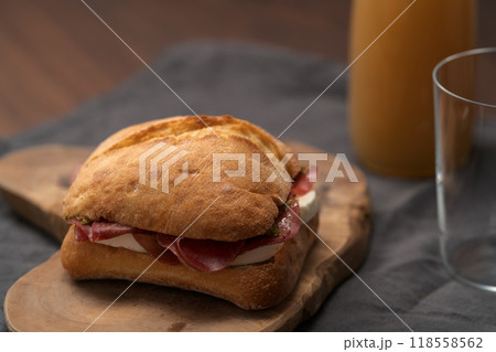 Sandwich with bresaola, mozzarella and pest on olive board with orange juice 118558562