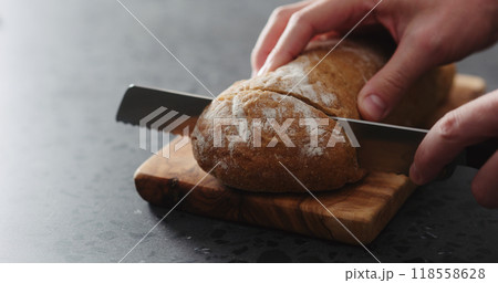 man hand slicing ciabatta on olive board 118558628