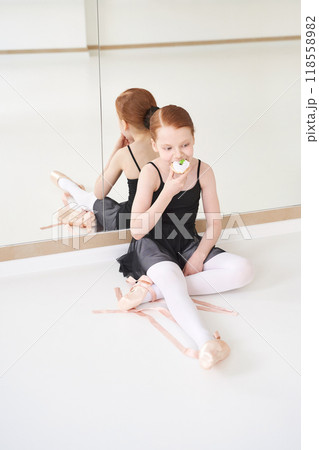 Young ballerina enjoying snack in dance studio reflecting relaxed atmosphere Young ballerina enjoying snack in dance studio reflecting relaxed atmosphere 118558982