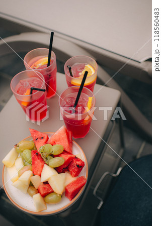 Close-up shot of a fruit cocktail and a food tray outdoors with the swimming pool in an out of focus background. 118560483