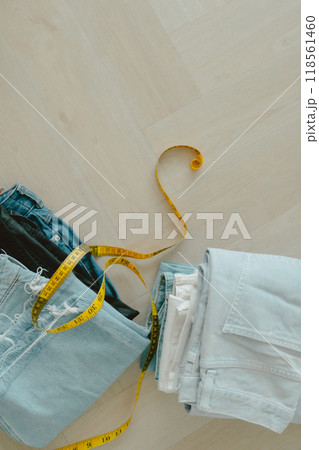Vertical photo of Black blue and white jeans on the floor with measuring tape. Vertical photo of Black blue and white jeans on the floor with measuring tape. 118561460