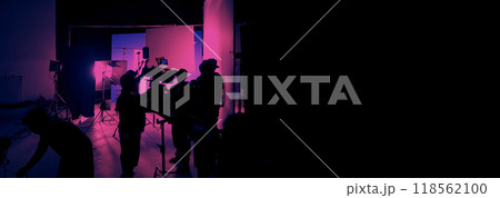 Silhouette of film crews and video camera on special dolly crane with film lights equipment and blue screen set. Film Production behind the scenes studio set in silhouette style. Behind video shooting Silhouette of film crews and video camera on special dolly crane with film lights equipment and blue screen set. Film Production behind the scenes studio set in silhouette style. Behind video shooting 118562100