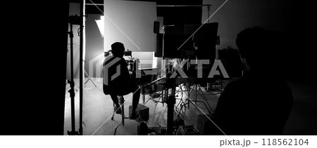 Silhouette of film crews and video camera on special dolly crane with film lights equipment and blue screen set. Film Production behind the scenes studio set in silhouette style. Behind video shooting Silhouette of film crews and video camera on special dolly crane with film lights equipment and blue screen set. Film Production behind the scenes studio set in silhouette style. Behind video shooting 118562104