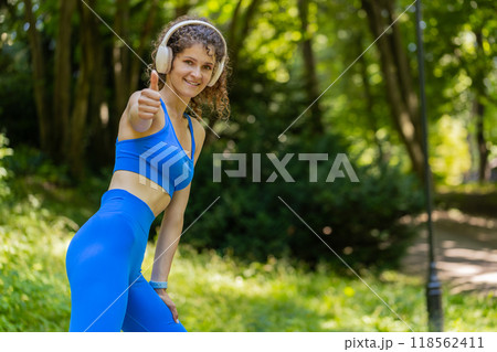 Athletic fitness sport motivated runner girl training marathon run, starting race showing thumb up 118562411