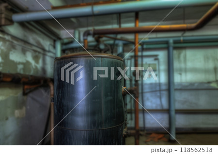 Old boiler room in a dirty old basement of building with rust and debris. Rusty pipes of the boiler room. An old metal boiler that generates heat and delivers it to the house through a pipeline. 118562518