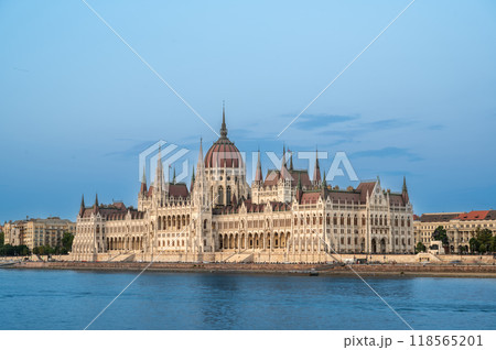 Budapest, Hungary. August 25, 2022. Amazing sunset shot of the parliament. The warm light of the golden hour enhances the beauty and elegance of the building. Three-quarter view. 118565201