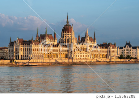 Budapest, Hungary. August 25, 2022. Amazing sunset shot of the parliament. The warm light of the golden hour enhances the beauty and elegance of the building. Three-quarter view. 118565209