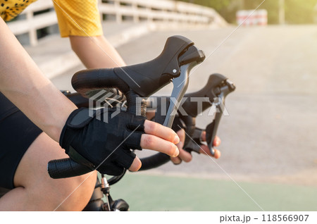 Cropped shot of cyclist hand wearing glove and holding a road bike brake. Brake is use to reduces the speed of a bicycle from moving. 118566907