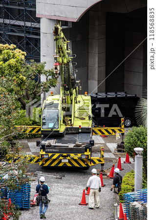 マンションの大規模修繕工事の工事現場で足場など仮設工事資材を高所に吊り上げるクレーン車 マンションの大規模修繕工事の工事現場で足場など仮設工事資材を高所に吊り上げるクレーン車 118568835