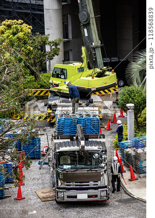 マンションの大規模修繕工事の工事現場で足場など仮設工事資材を高所に吊り上げるクレーン車 118568839