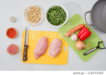 Preparing ingredients for a chicken stir-fry with fresh vegetables and spices, overhead view 118573383