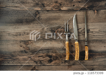 Rustic wooden kitchen table showcasing three high-quality essential barbecue tools 118573399