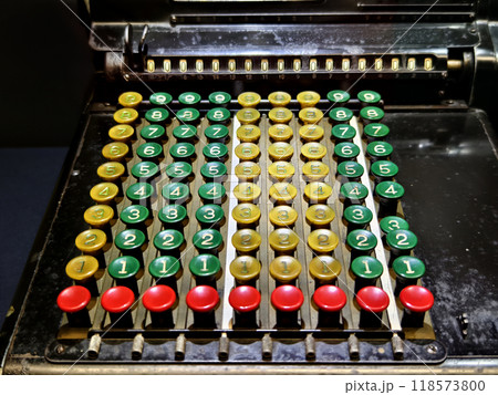 An old fashioned adding machine features a drawer located underneath it 118573800