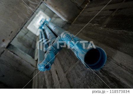 A bright blue pipes attached to a solid concrete wall 118573834